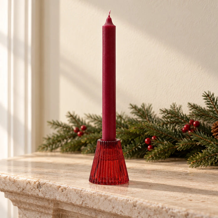 Burgundy glass dinner candle holder with red taper on a Christmas mantel