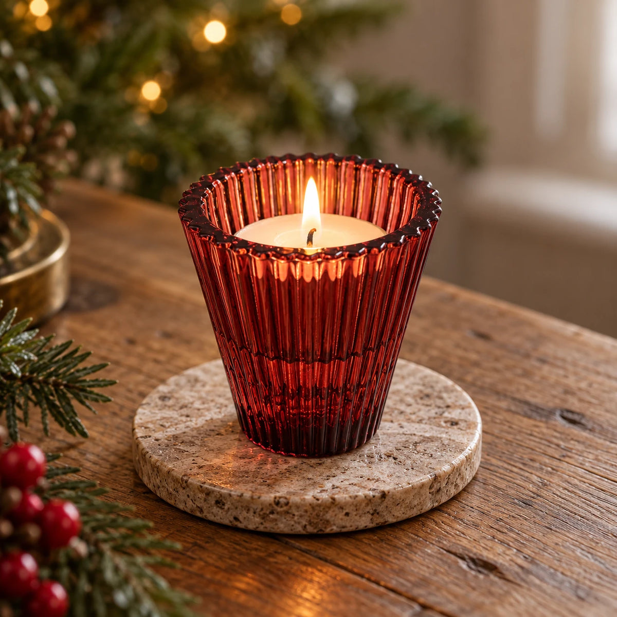 Burgundy ribbed glass holder with a lit tealight on a stone coaster at Christmas