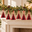 Six burgundy paper Christmas trees suspended beneath a festive mantel garland.