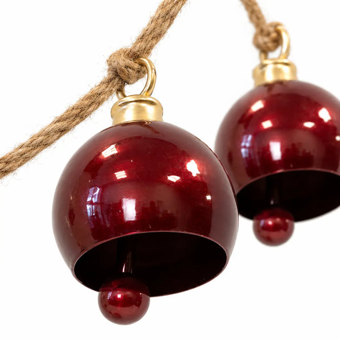 Close-up of glossy burgundy metal bells with ball clappers and gold-coloured fittings