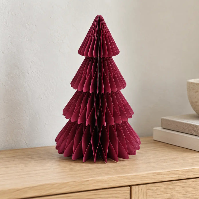 Burgundy folded paper Christmas tree on a pale oak console beside books.