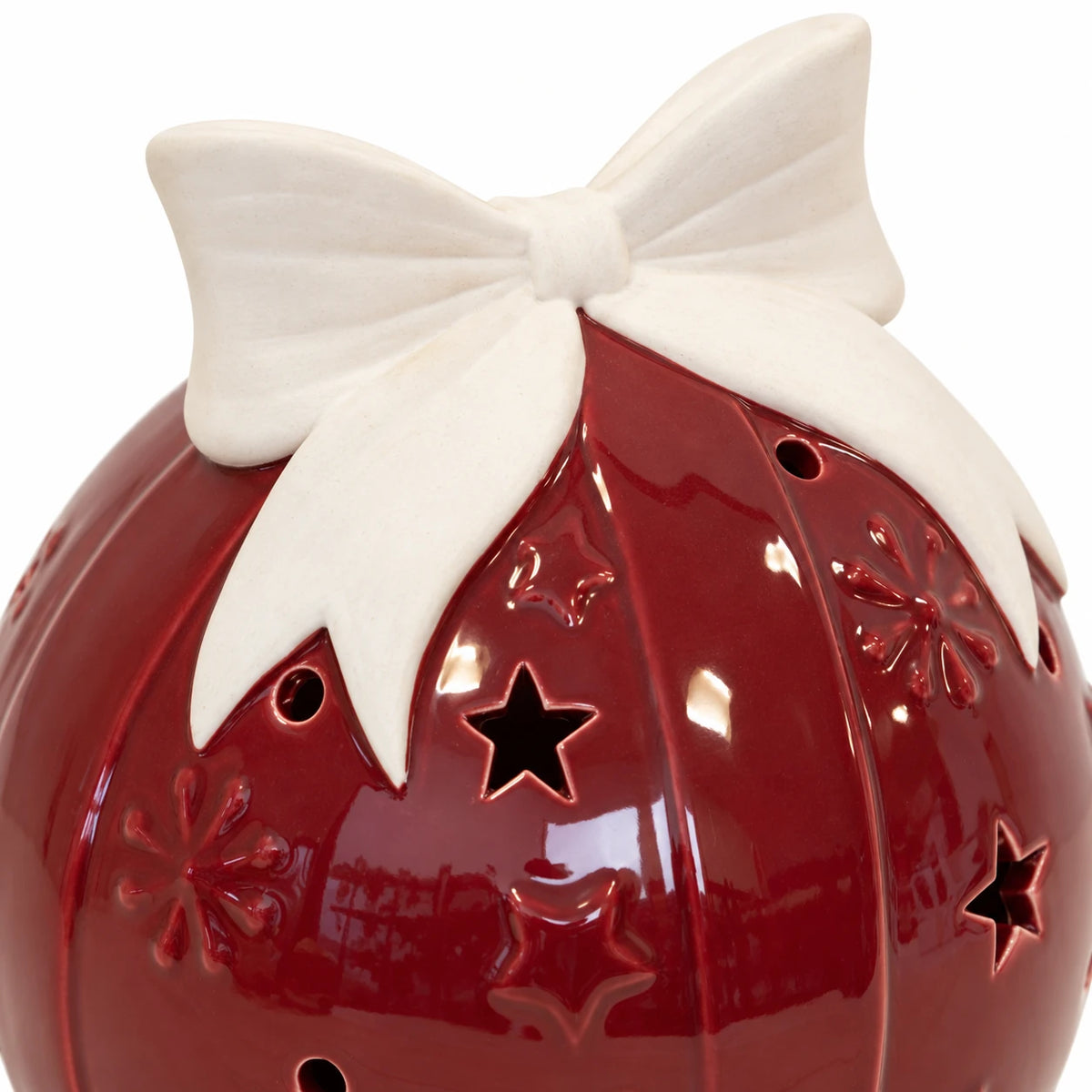 Close-up of the ivory ceramic bow and star cut-outs on a burgundy red bauble