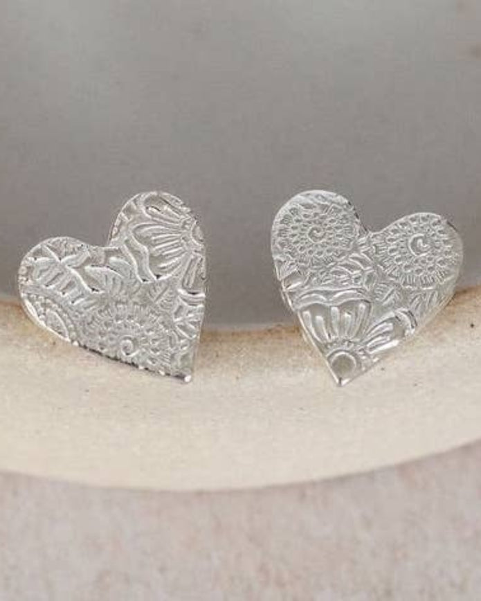 Silver heart-shaped earrings on a white ceramic dish