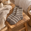 Cappuccino striped cosy socks arranged on a rustic oak bedside bench