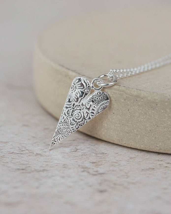 Silver necklace with an ornate pendant on a light background