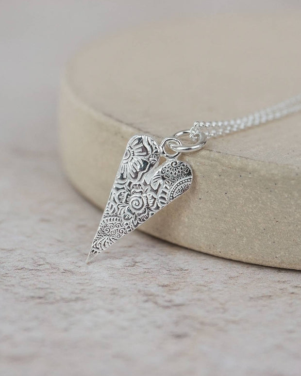 Silver necklace with an ornate pendant on a light background