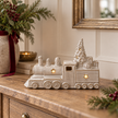 Glazed ceramic LED Christmas train styled on an oak console with winter greenery