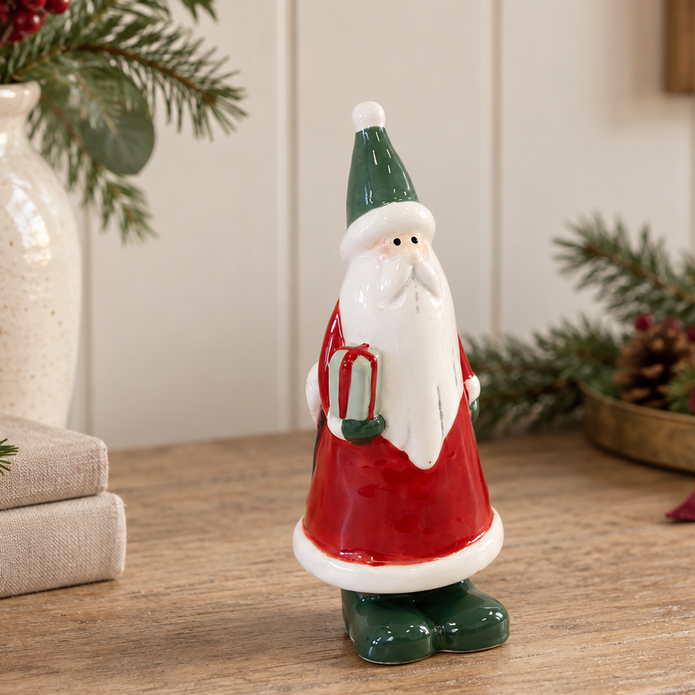 Small Red Ceramic Santa Holding a Present styled in a warm neutral Christmas interior