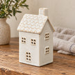 Unlit natural glazed ceramic house displayed on a rustic oak side table