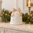 White ceramic LED bell with bow on a limestone Christmas mantel