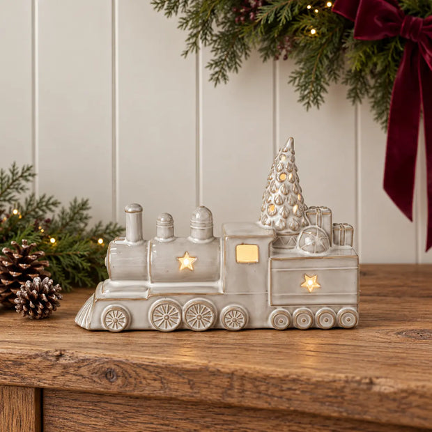 Neutral ceramic light up Christmas train on a console with burgundy and evergreen seasonal decor