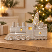Light up ceramic Christmas train on an oak console beside a Christmas tree