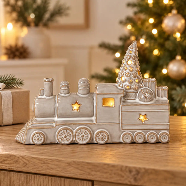 Glazed ceramic Christmas LED train ornament by Satchville, illuminated with lights, perfect for holiday decorations on a mantel or console.