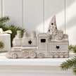Grey glazed ceramic Christmas train on a white shelf with festive greenery
