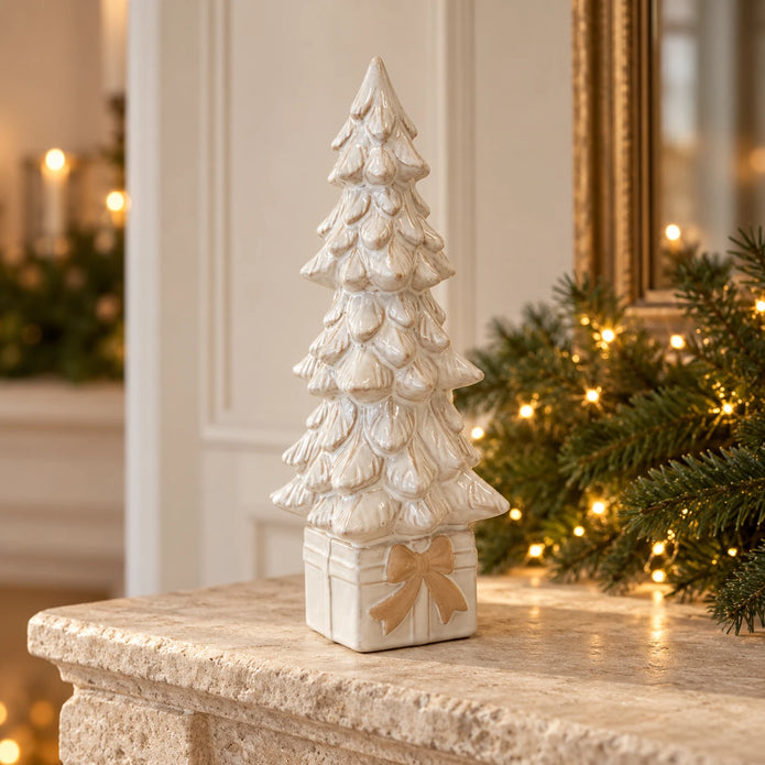 Ivory ceramic Christmas tree on a present-shaped base on a Christmas mantel.