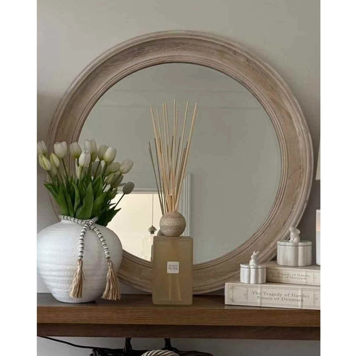 Chloe round washed wood framed mirror by Hill Interiors, hanging on a wall, showcasing its circular design and rustic wood frame.