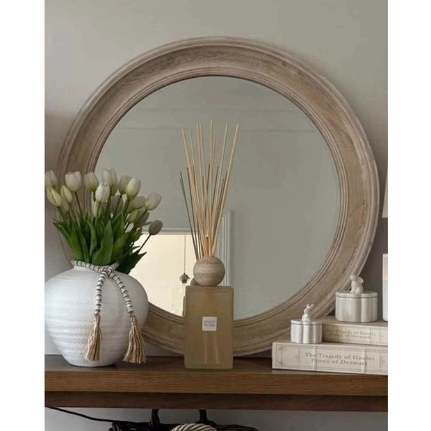 Chloe round washed wood framed mirror by Hill Interiors, hanging on a wall, showcasing its circular design and rustic wood frame.