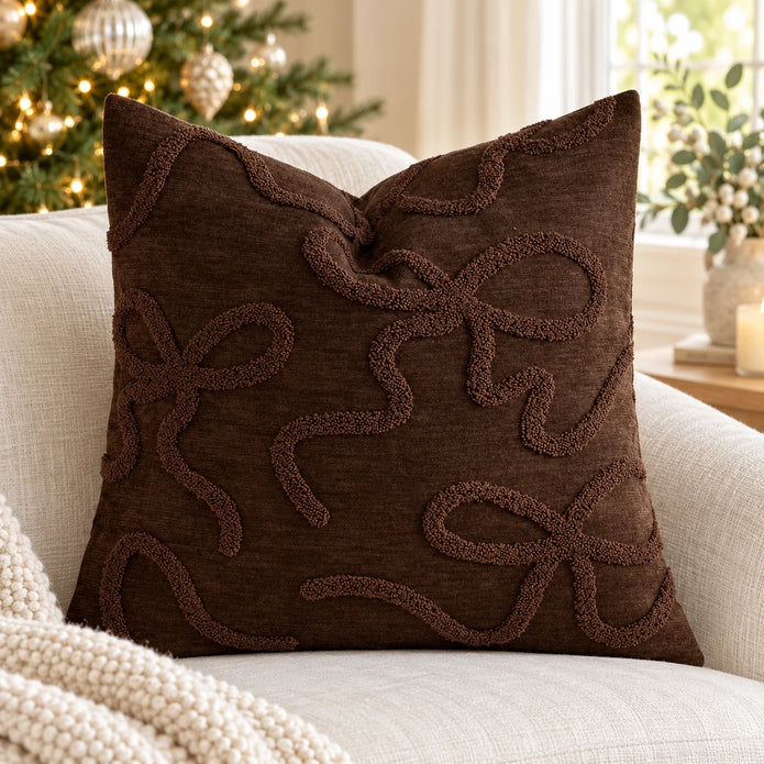 Chocolate brown raised bow cushion cover styled on a linen armchair beside a Christmas tree