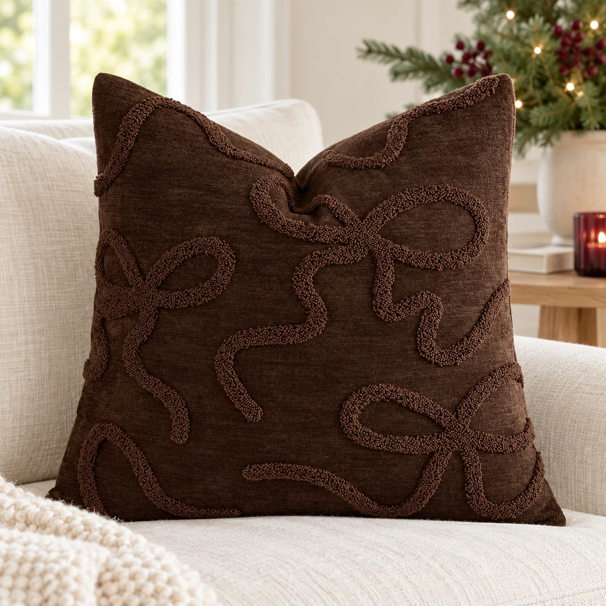 Chocolate brown bow bouclé cushion cover styled on a cream sofa in a light Christmas room