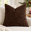 Chocolate brown bow bouclé cushion cover styled on a cream sofa in a light Christmas room