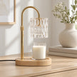 Clear glass candle warmer switched off on a pale oak dresser