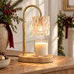 Clear glass candle warmer with gold frame on an oak console in a Christmas setting