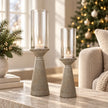 Concrete candle holders with clear glass shades and lit white tealights on a stone table