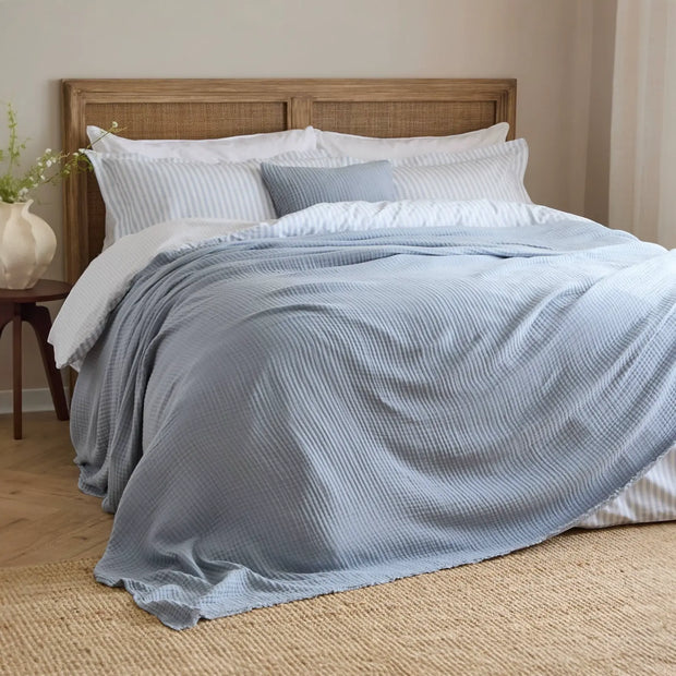 Riva Home Ocean Blue Muslin Cotton Throw Bed Cover, soft furnishings with a smooth, lightweight ocean blue fabric draped on a bed.