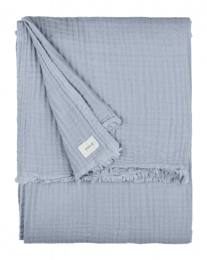 Riva Home ocean blue muslin cotton throw bed cover displayed on a bed, showcasing soft, lightweight furnishings for cozy bedroom decor.