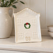 Cosy Christmas House Plate on a neutral dresser shelf beside a ceramic jug.
