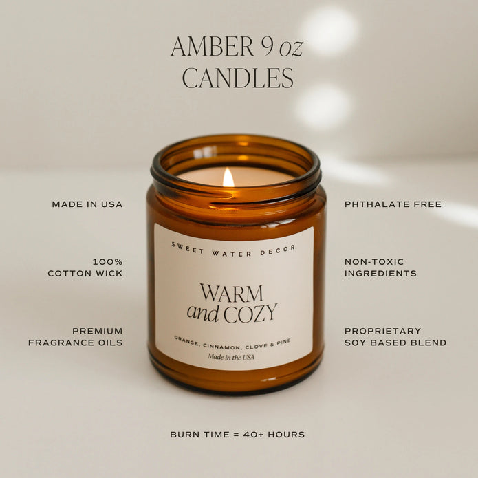 Sweet Water Decor amber 9 oz candle feature graphic, illustrated with a lit Warm and Cozy candle.