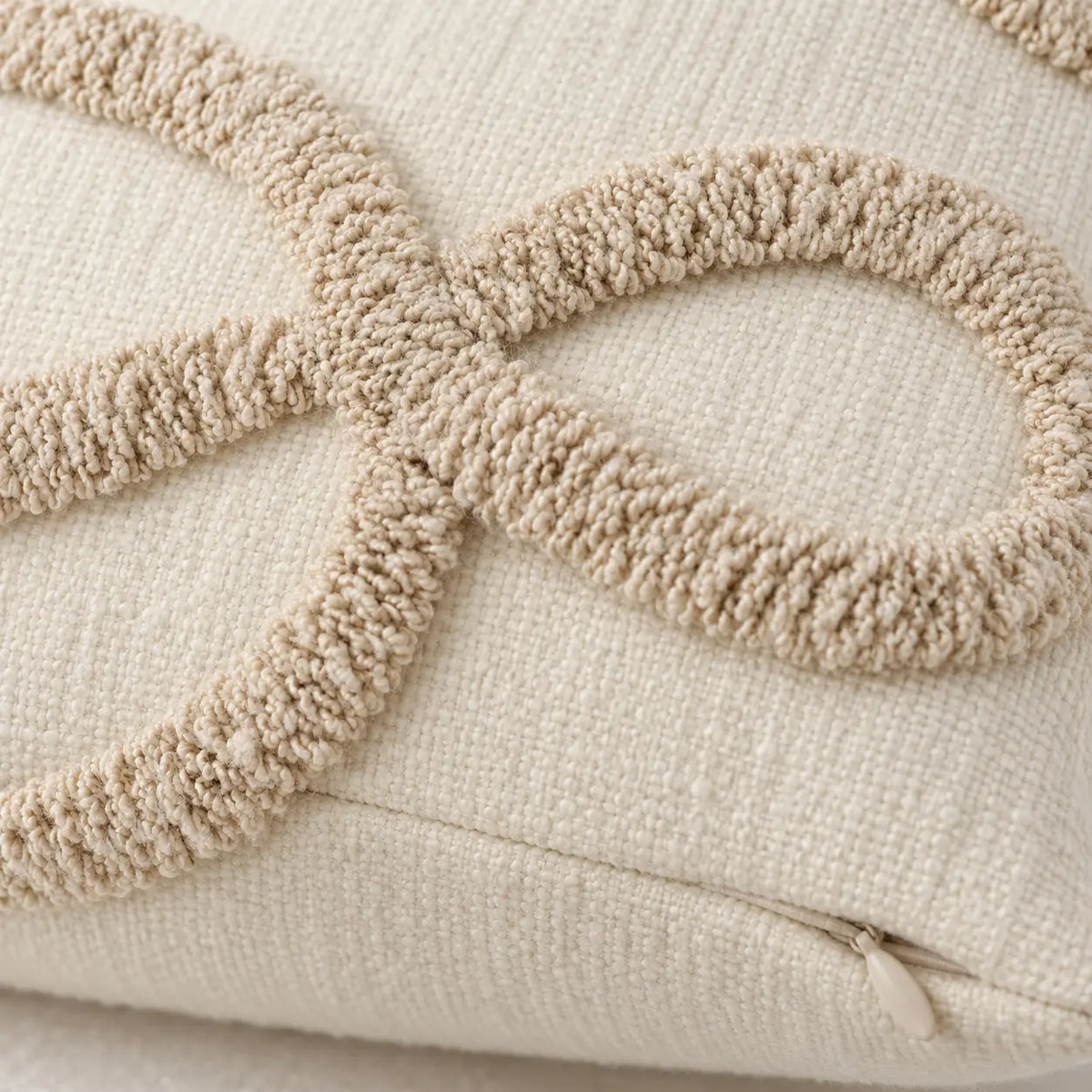 Close-up of the raised beige bow-loop bouclé texture and hidden zip on the cream rectangular cushion cover.