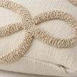 Close-up of the raised beige bow-loop bouclé texture and hidden zip on the cream rectangular cushion cover.