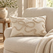 Cream and beige bow rectangle bouclé lumbar cushion styled on a cream armchair in a light country reading nook.