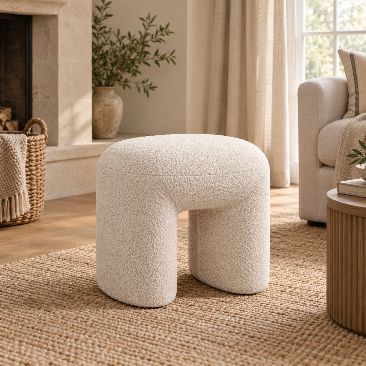 Cream boucle arched footstool styled in a warm neutral living room