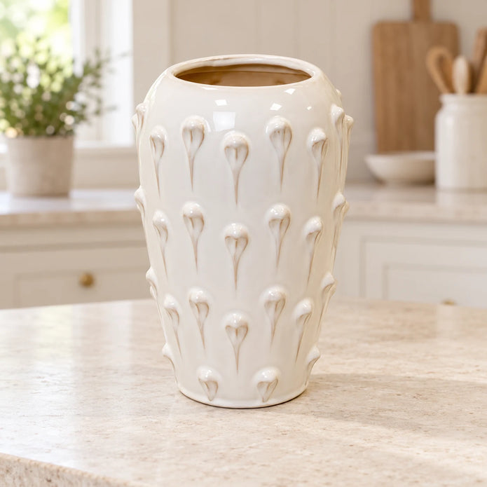 large ivory cream ceramic bobble vase on a pale stone counter in a bright cream kitchen
