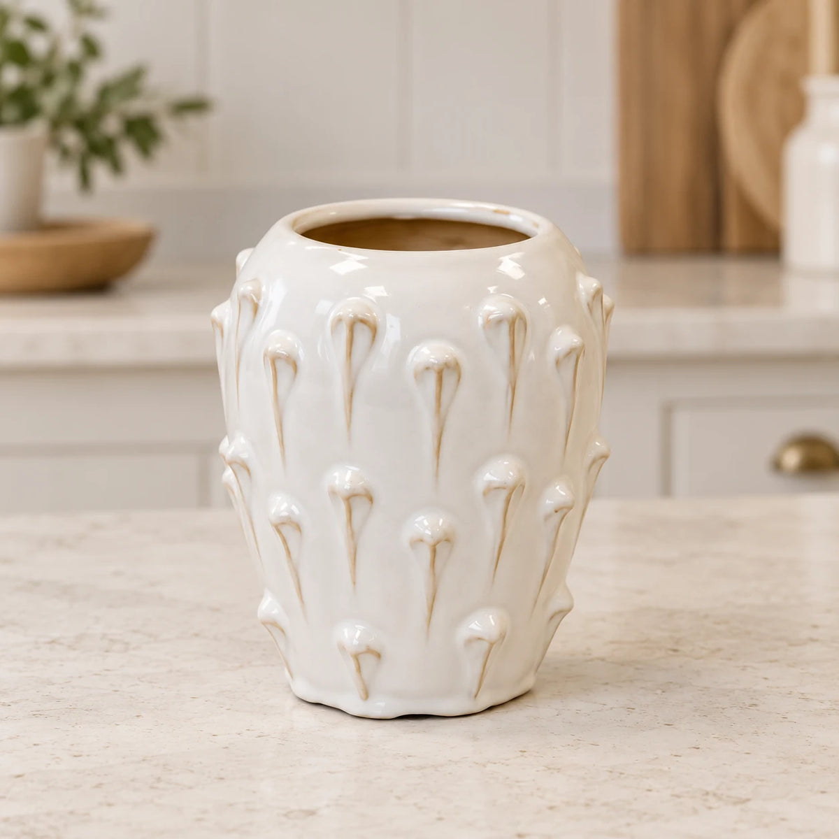 small ivory cream ceramic bobble vase on a pale stone counter in a bright cream kitchen