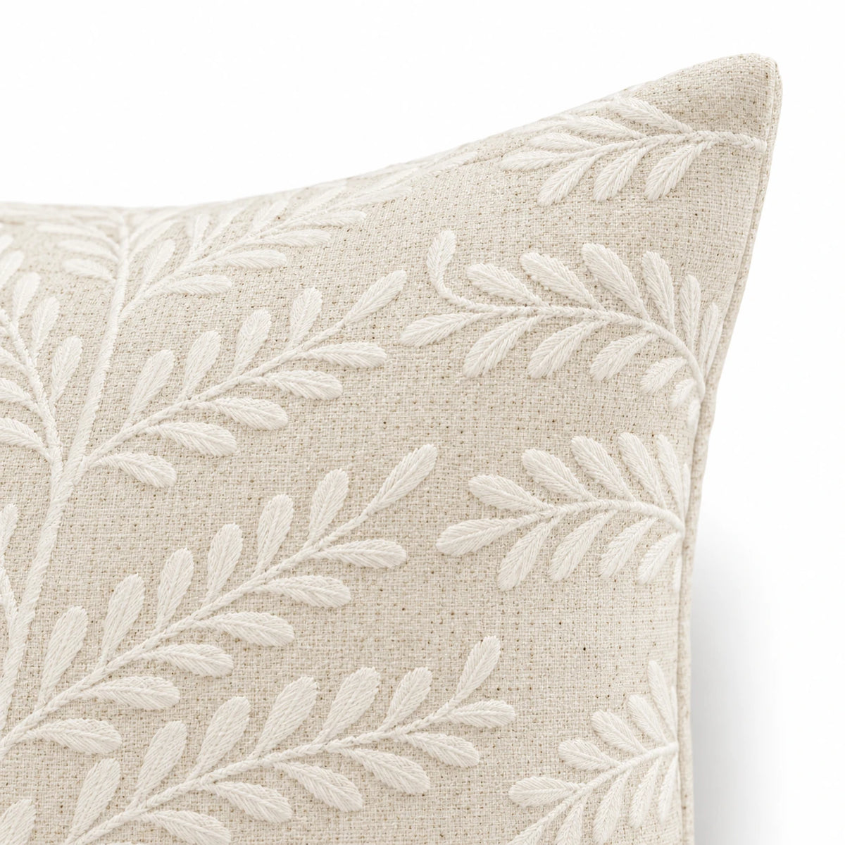 Cream Fern Embroidered Cushion Cover, close-up of the embroidered front corner and plain sewn edge against white.