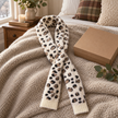 Cream fluffy leopard print pull-through scarf styled on an oatmeal throw