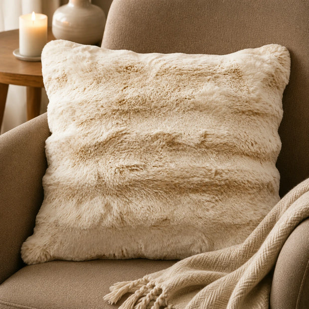 Cream Luxury Faux Fur Cushion, cream faux fur cushion on an armchair beside candlelight