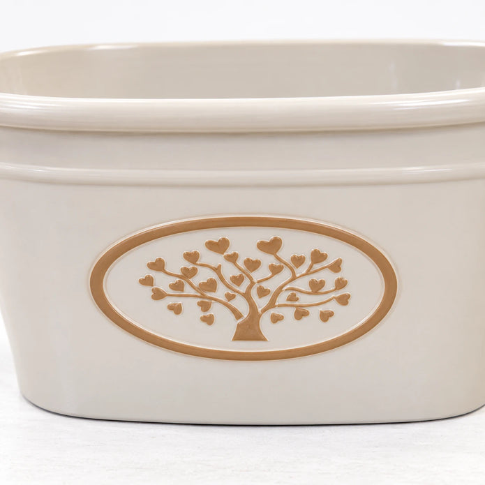 Close-up of the raised warm taupe tree and heart-leaf medallion on the cream planter.