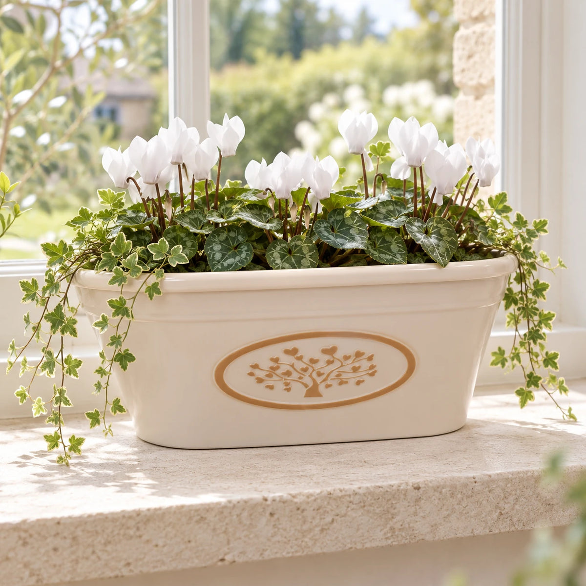 Cream recycled plastic oval planter styled with white cyclamen and trailing greenery on a light stone windowsill.