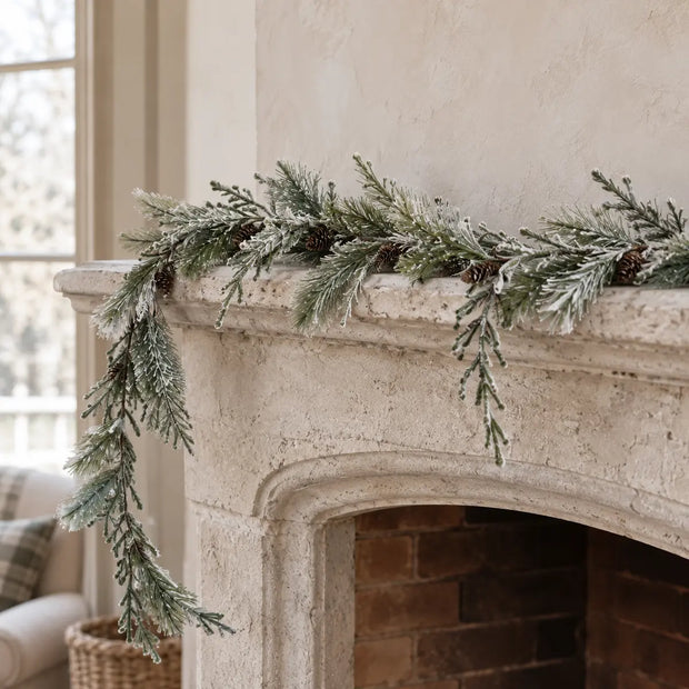 Snowy spruce and Norfolk pine garland draped across a stone mantel