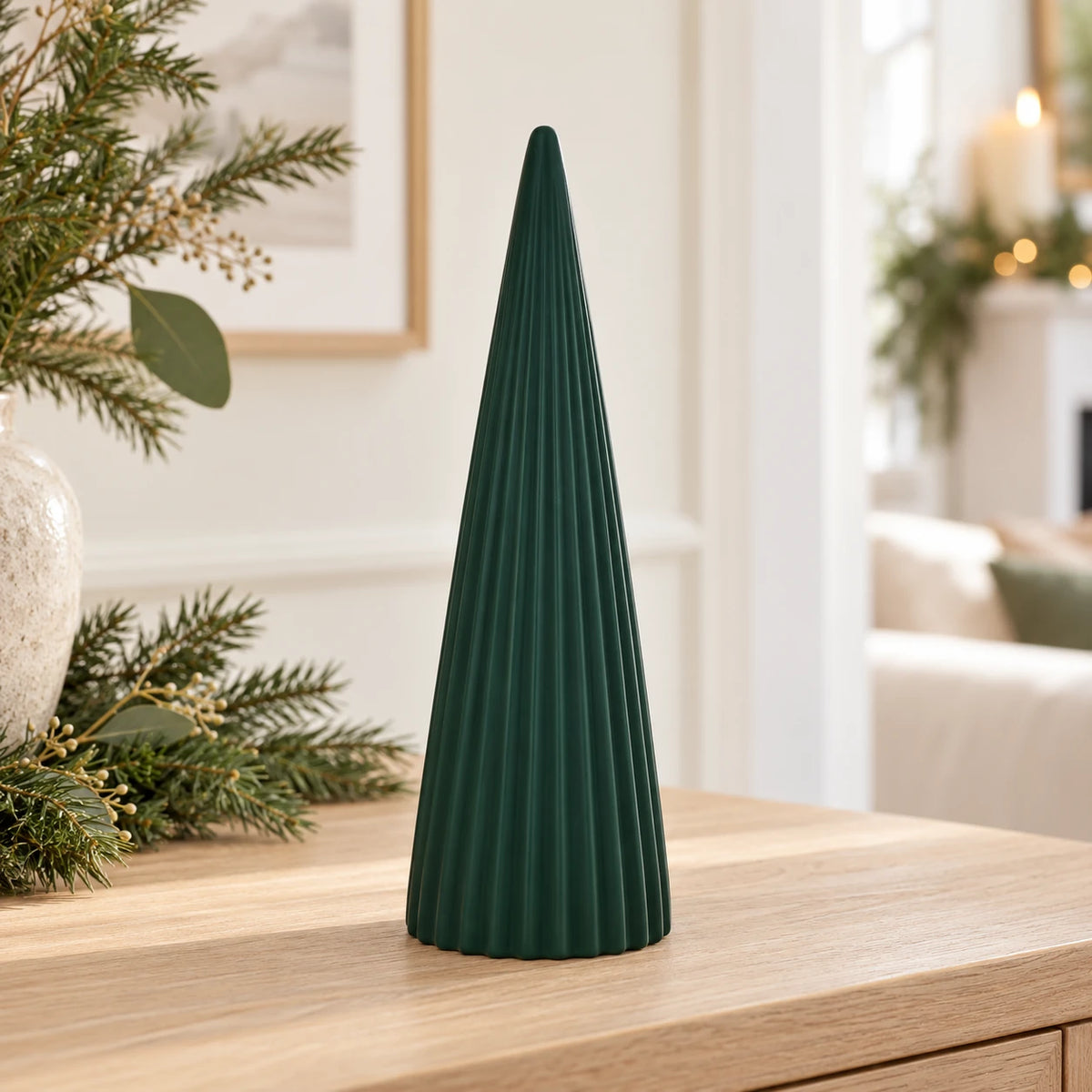 Dark green ribbed ceramic Christmas tree on an oak console in a bright neutral room