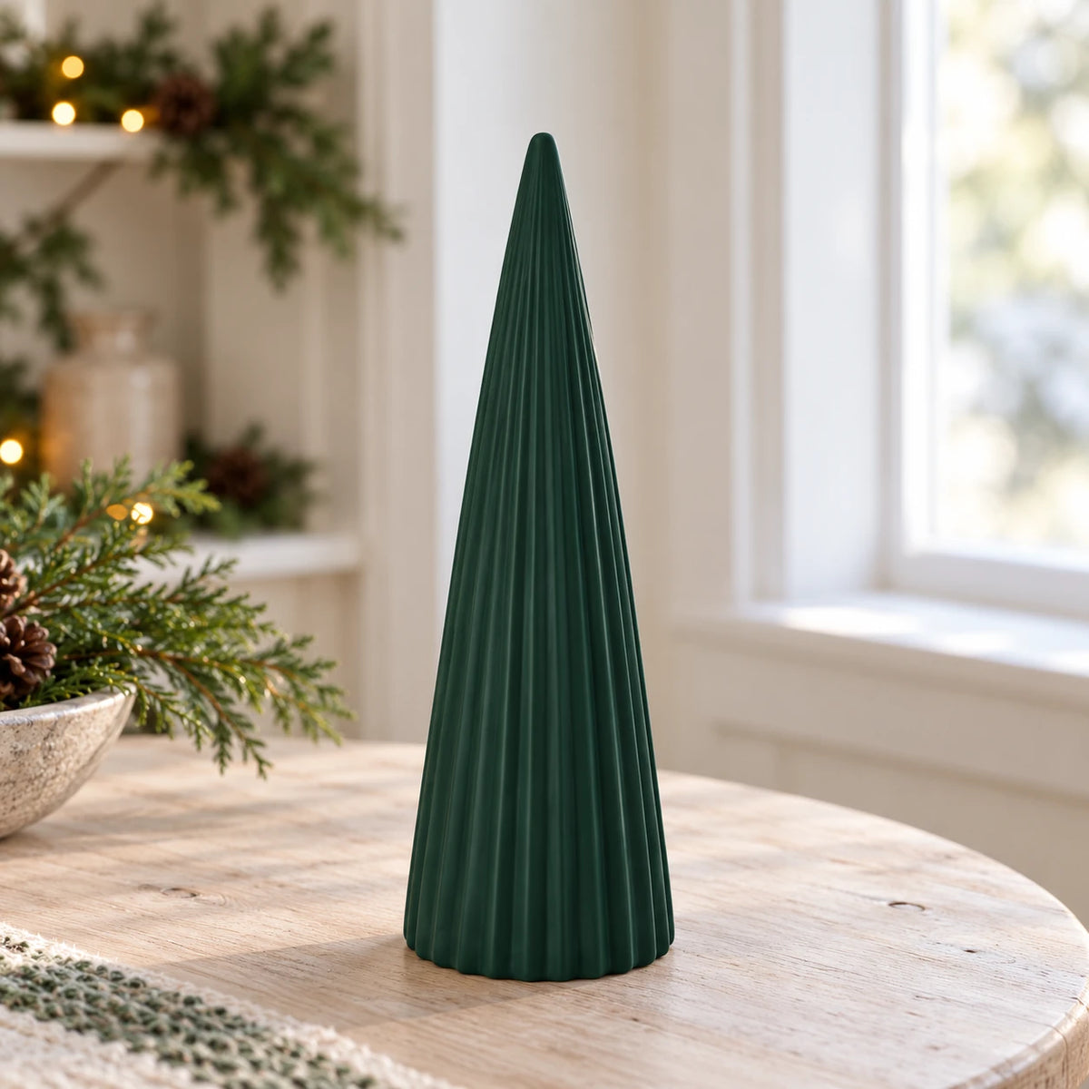 Dark green ribbed ceramic tree on a wooden side table beside a bright window