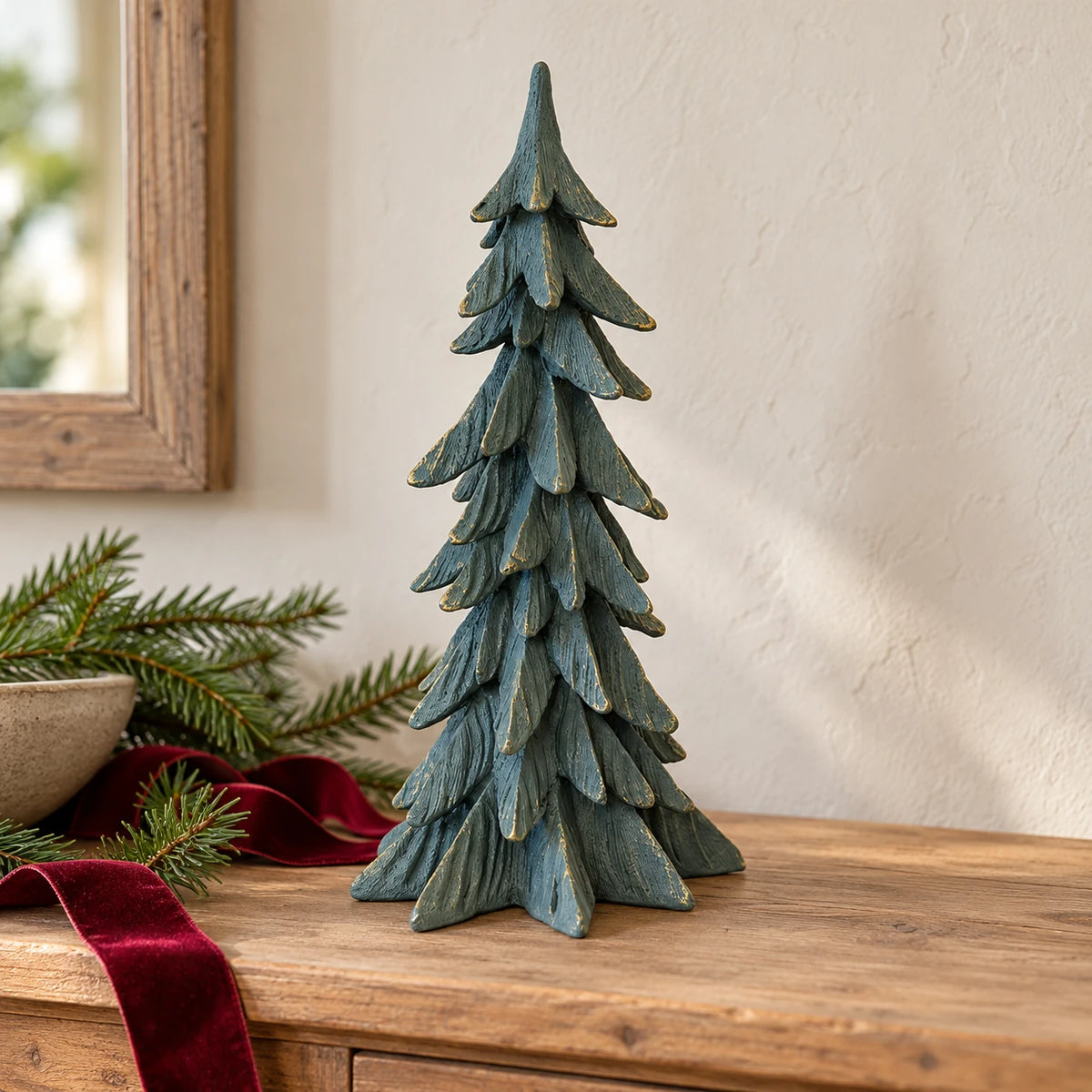 Tall dark sage resin Christmas tree with gold edging on an oak console with fir and burgundy ribbon.