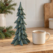Tall sage resin Christmas tree beside a mug of tea on a country kitchen counter.