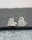 Silver heart-shaped earrings on a dark stone surface