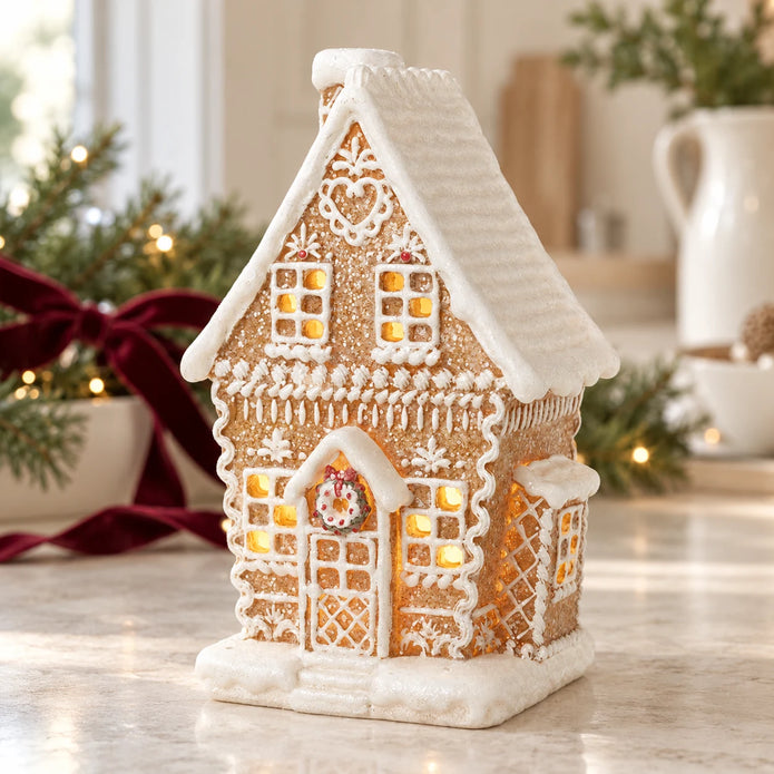Decorated gingerbread house with white icing and heart detail on a bright Christmas kitchen worktop