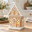 Decorated gingerbread house on an oak breakfast table in a light Christmas kitchen